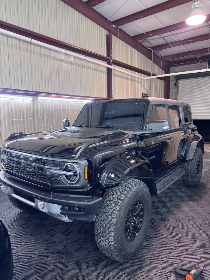 Black Ford Bronco Raptor with tinted windows on a checkered shop floor