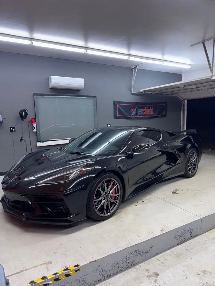 Black C8 Corvette under the LED light bars in the bay