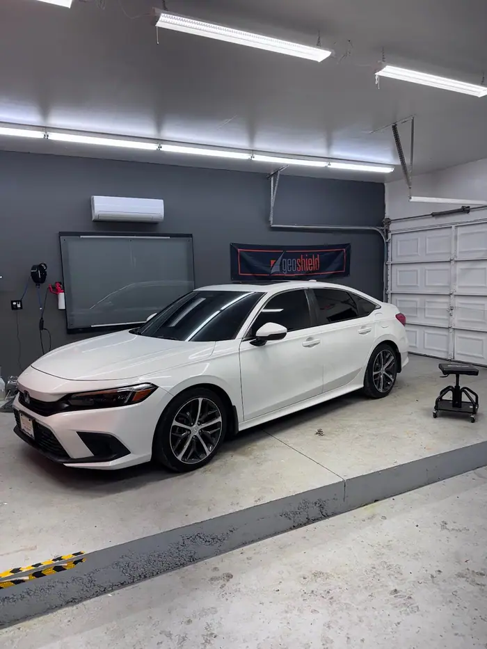 White Honda Civic sedan with fresh window tint in the Stealth Tint and PPF bay