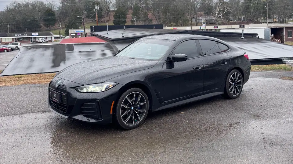 Dark gray BMW 4 Series Gran Coupe with tinted windows on a damp lot
