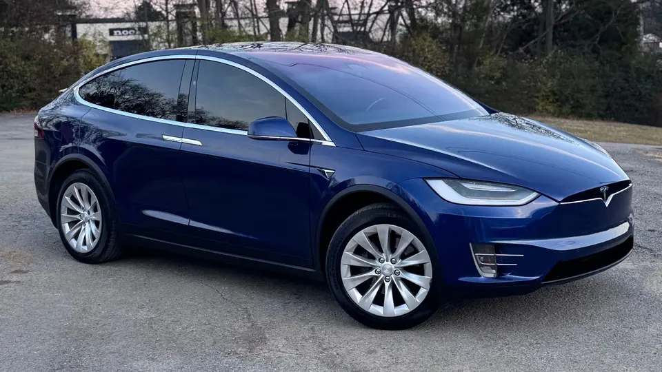 Blue Tesla Model X with tinted glass parked at dusk