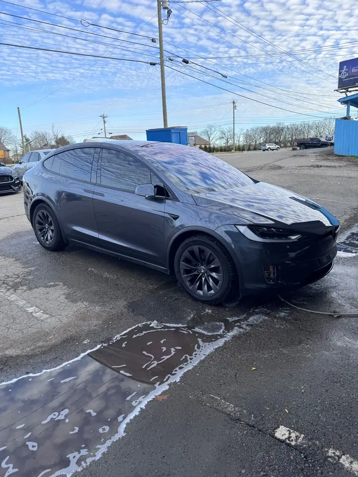 Dark gray Tesla Model X on a wet lot after service