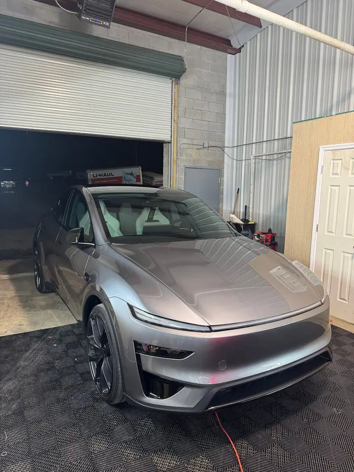 Silver Tesla Model Y on a checkered shop floor