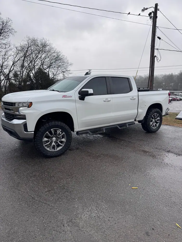 White Chevrolet Silverado with tinted windows on a wet lot