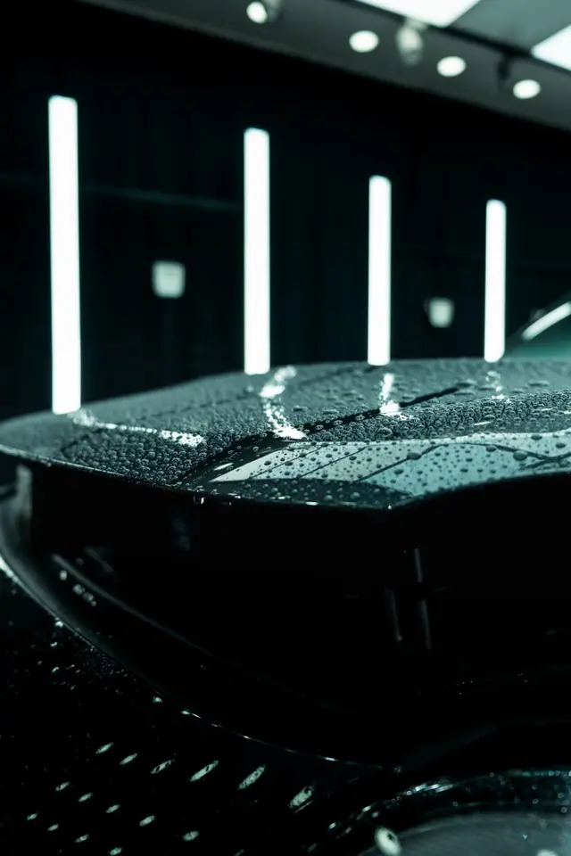 Water beading on a dark coated hood under studio light bars (stock photo)
