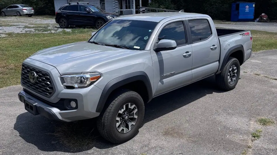 Silver Toyota Tacoma with tinted windows outside the red-roofed Stealth Tint and PPF shop